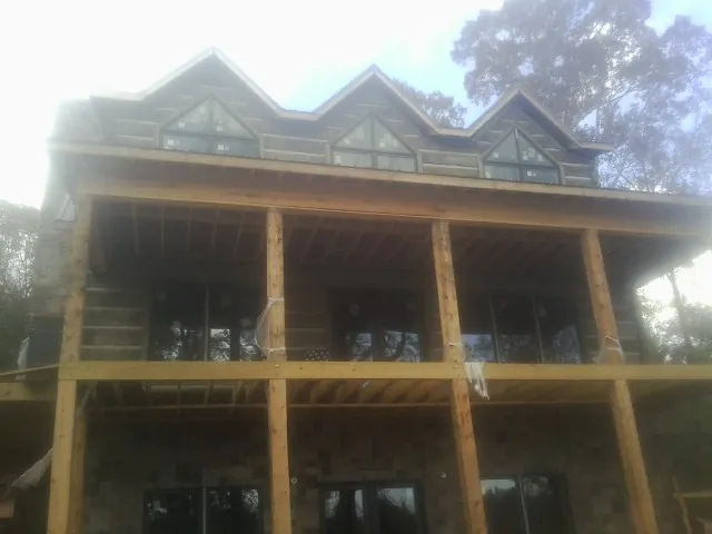 Dormers and porch framing on a large log home under construction — Roof Coating work by our crew in Hill City