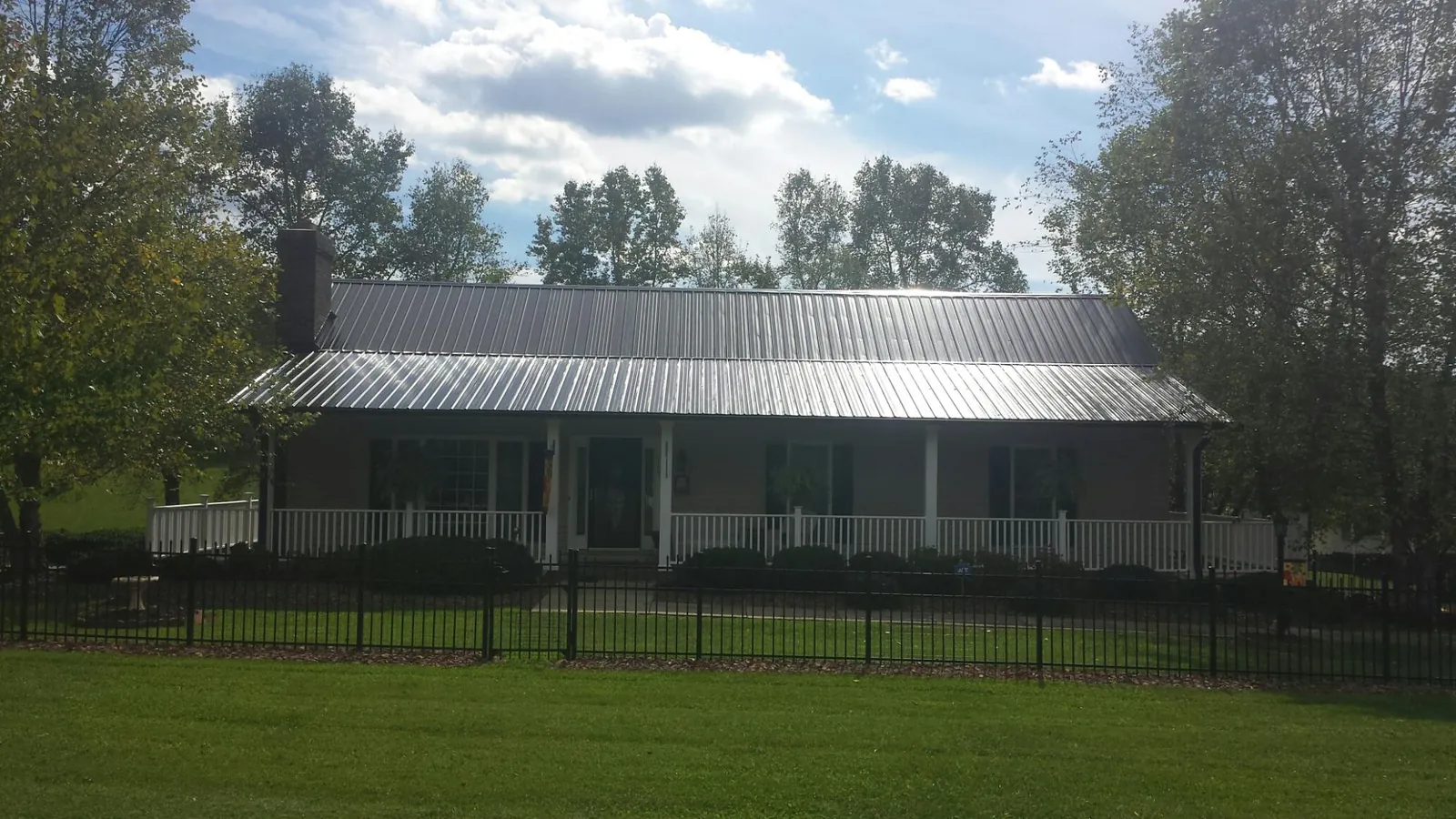 Gray metal roof on a brick ranch with a full width front porch — Gutter Guard Installation work by our crew in Hill City