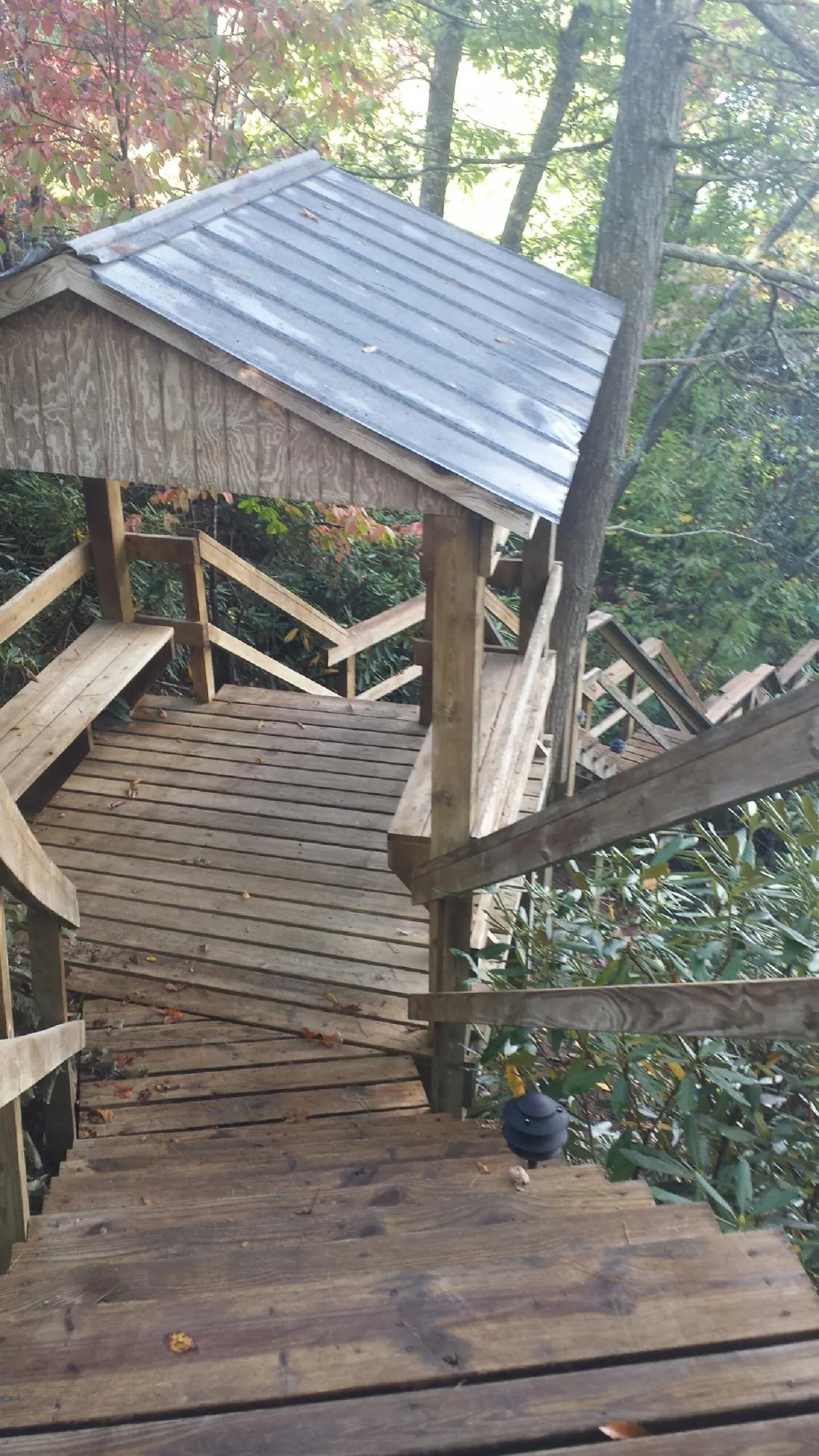 Metal roofed shelter over wooden steps on a wooded walkway — Skylight Repair & Installation work by our crew in Hill City