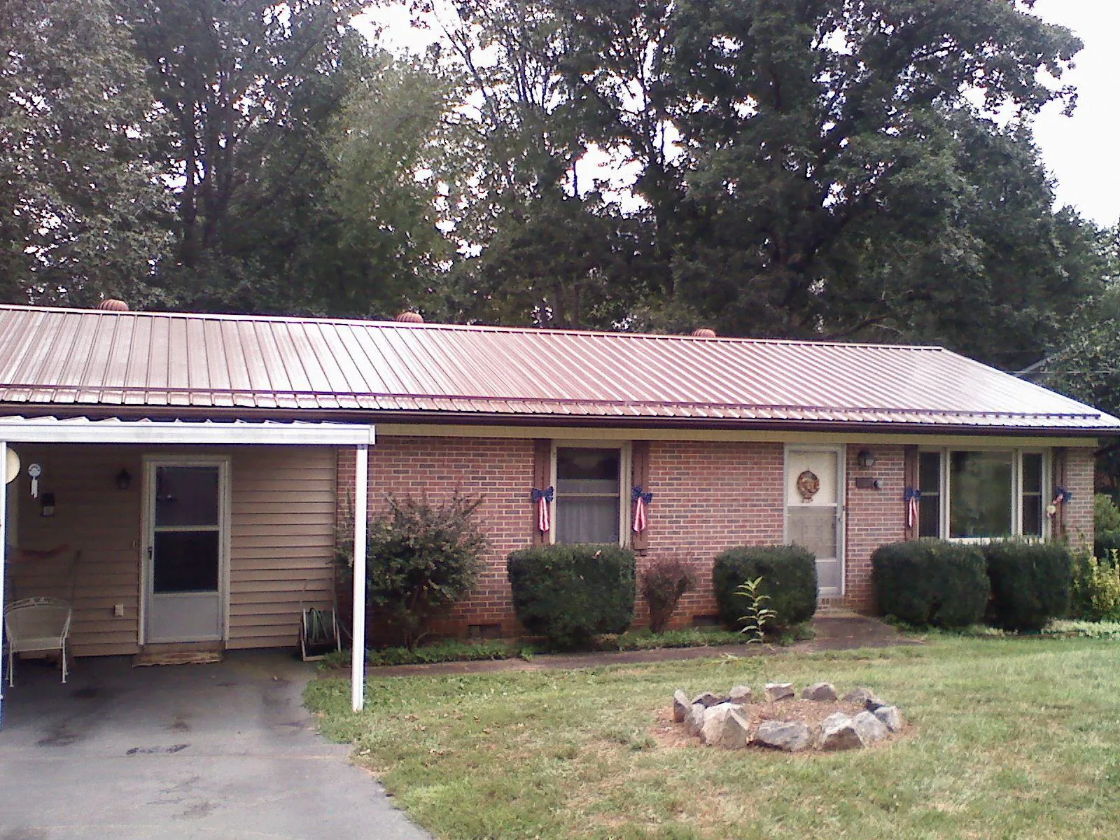 Bronze metal roof and carport on a brick ranch home — Roof Repair work by our crew in Hill City