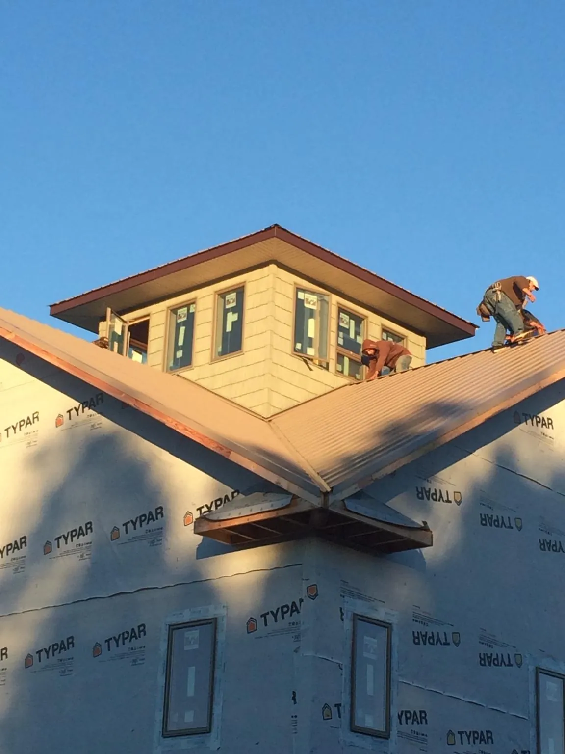 Roofers working around a rooftop cupola on a new metal roof at sunset — Roof Waterproofing in Hill City by Roofing Brothers